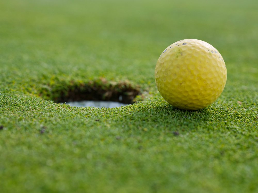 Golfball am Loch auf dem Grün
